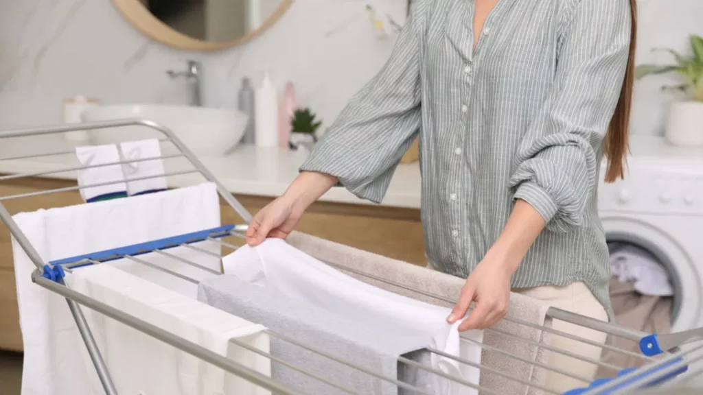 woman_hanging_clean_laundry_on_drying_rack_ss1924381058